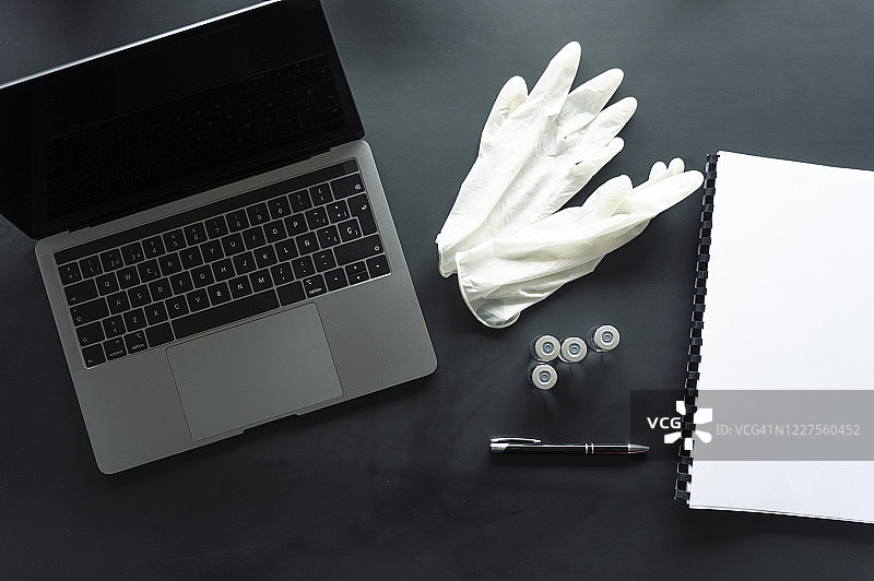 桌子上笔记本电脑旁的手套和螺旋笔记本的医疗样本俯视照片图片素材
