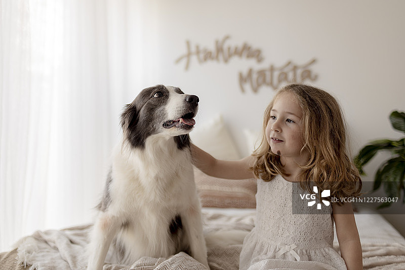 和狗狗坐在床上的小女孩肖像图片素材