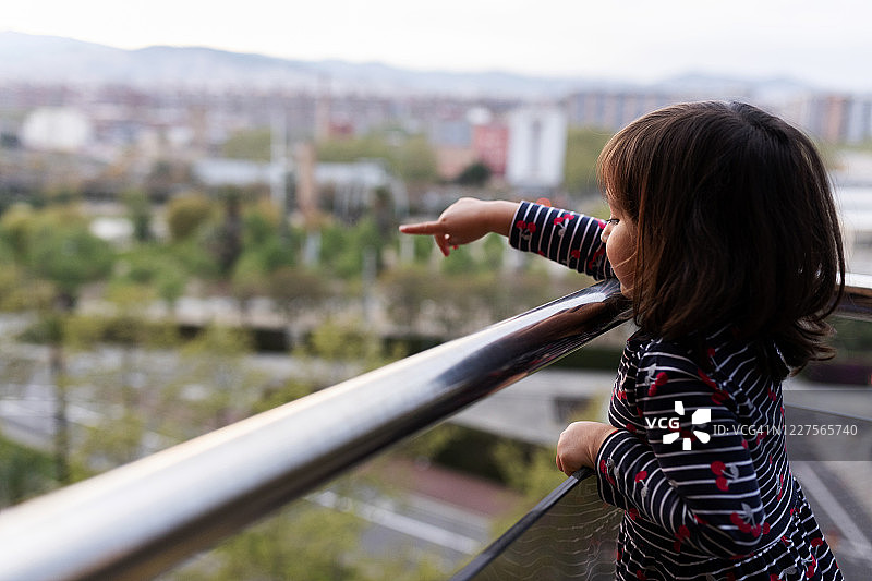 小女孩站在阳台上指着什么图片素材