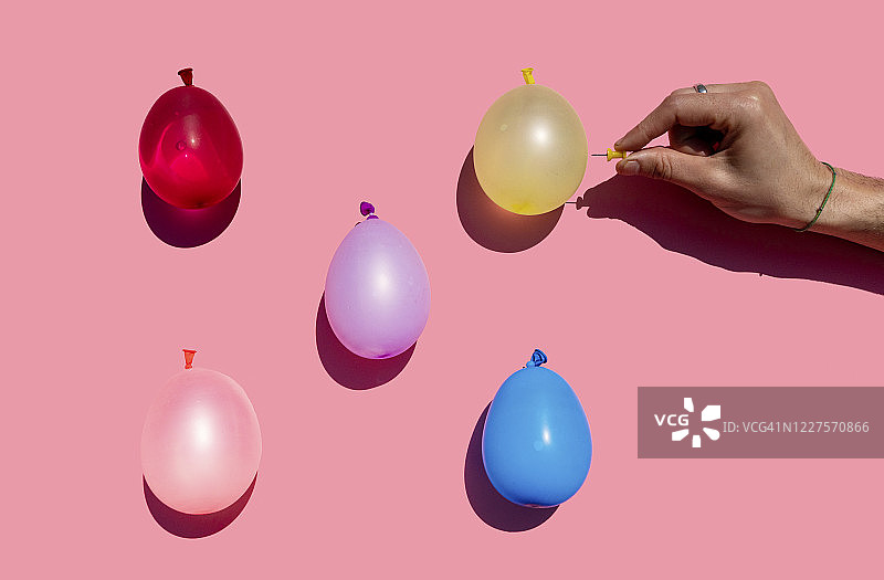 男人试图用图钉刺破彩色水球的影棚拍摄图片素材