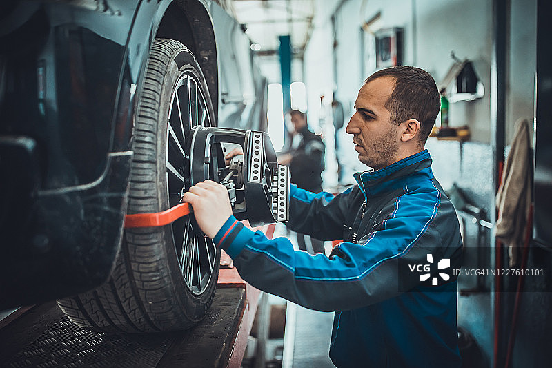汽车修理工在维修站调整汽车车轮定位设备图片素材