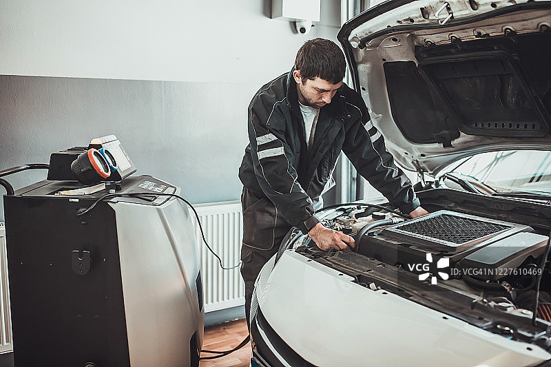 机械师在汽车修理店为汽车空调充气图片素材