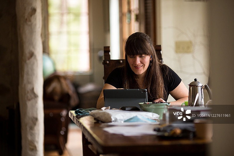 女子在家中厨房的餐桌旁工作图片素材