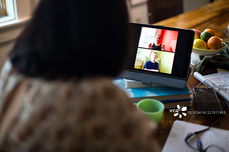 与年幼的孩子进行视频通话的肩上视角图片素材