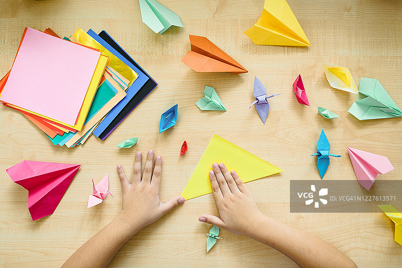 孩子的手在桌旁折纸。图片素材