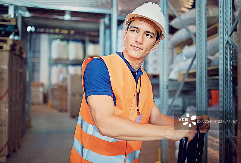 在仓库里拉托盘车的工人肖像图片素材