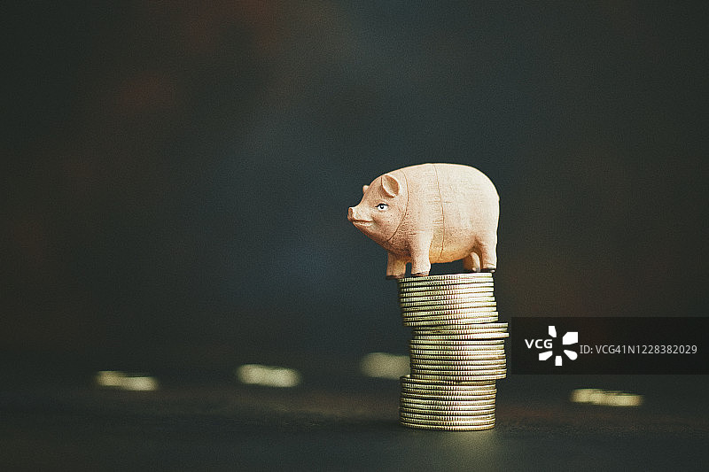 小猪存钱罐在金币堆上平衡：金融与储蓄图片素材