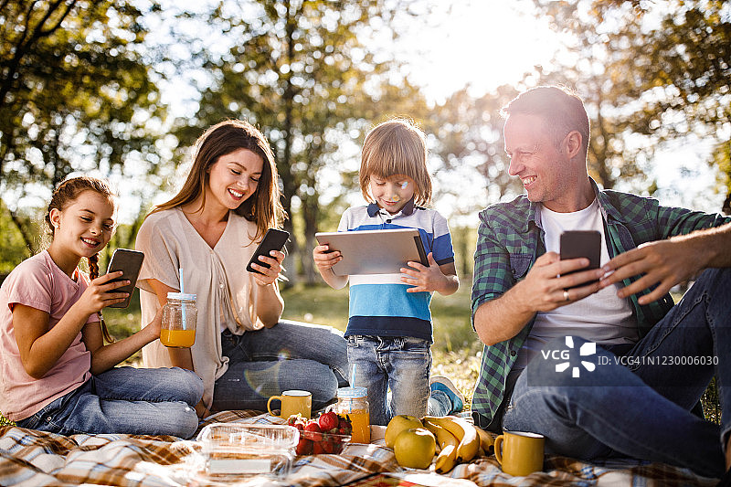 幸福家庭在野餐时使用无线技术图片素材