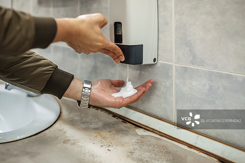 戴口罩的男人在公共卫生间洗手图片素材