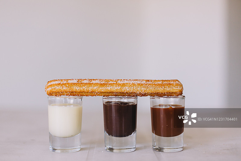 一根西班牙油条，搭配炼乳、巧克力酱和焦糖酱图片素材