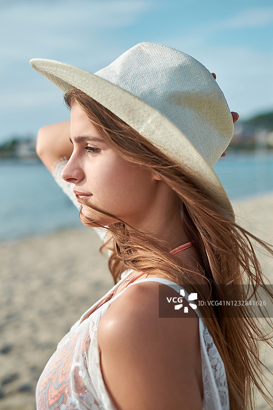 年轻女人在海滩头戴遮阳帽图片素材