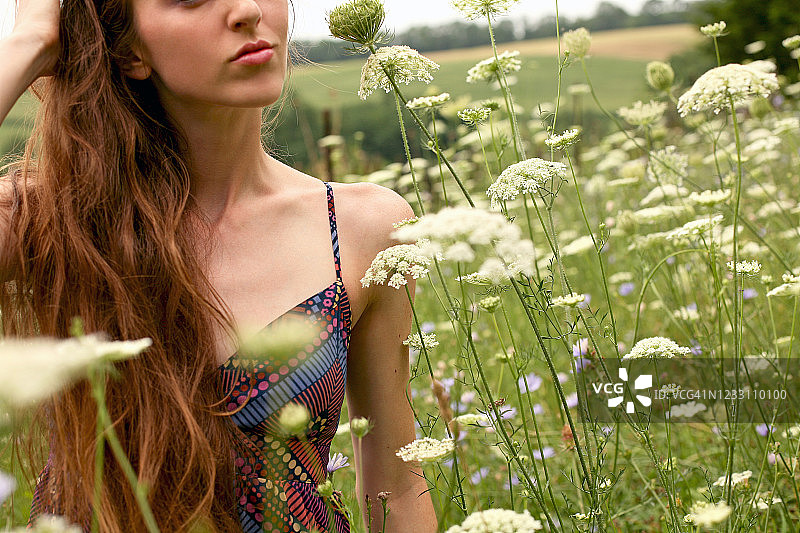 年轻女人在美丽的野花田中图片素材