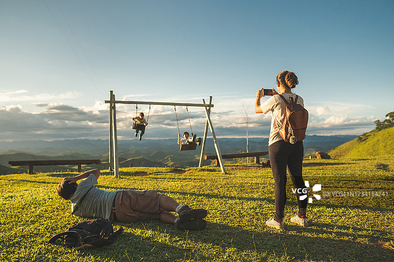家庭在自然公园的秋千上玩耍图片素材