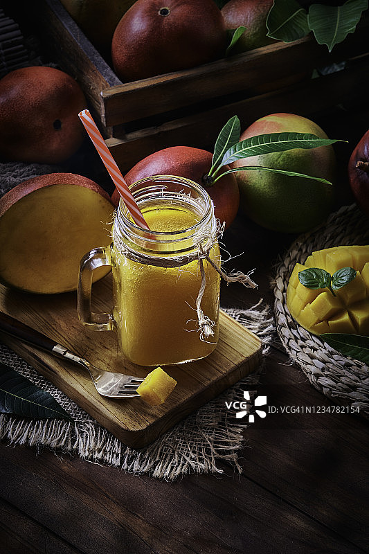 乡村厨房木桌上梅森罐里的芒果冰沙果汁和水果图片素材