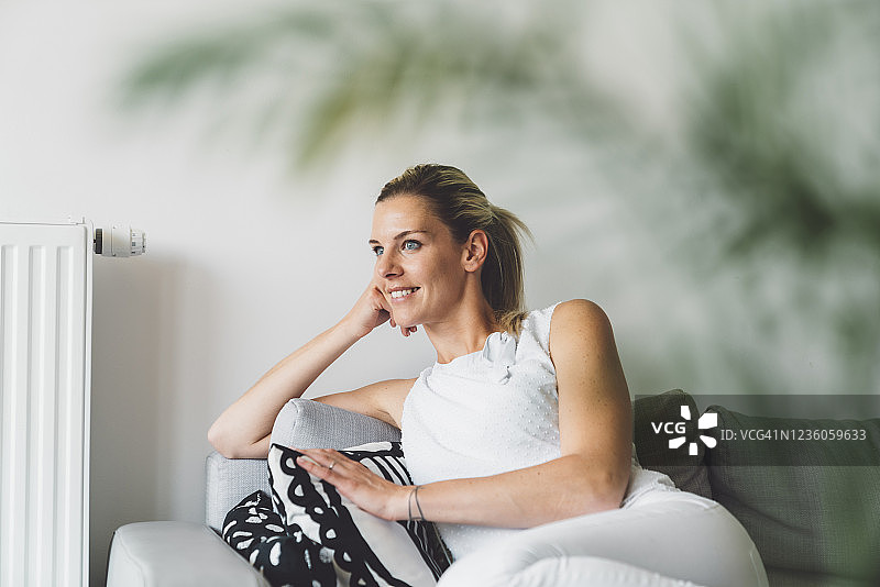 坐在沙发上向窗外看的金发女人图片素材