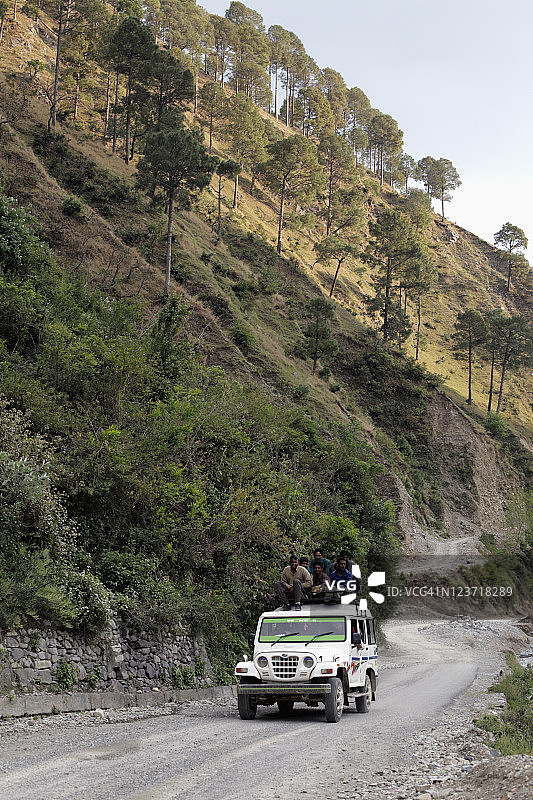 在印度喜马拉雅山脉，男子们坐在卡车顶上图片素材