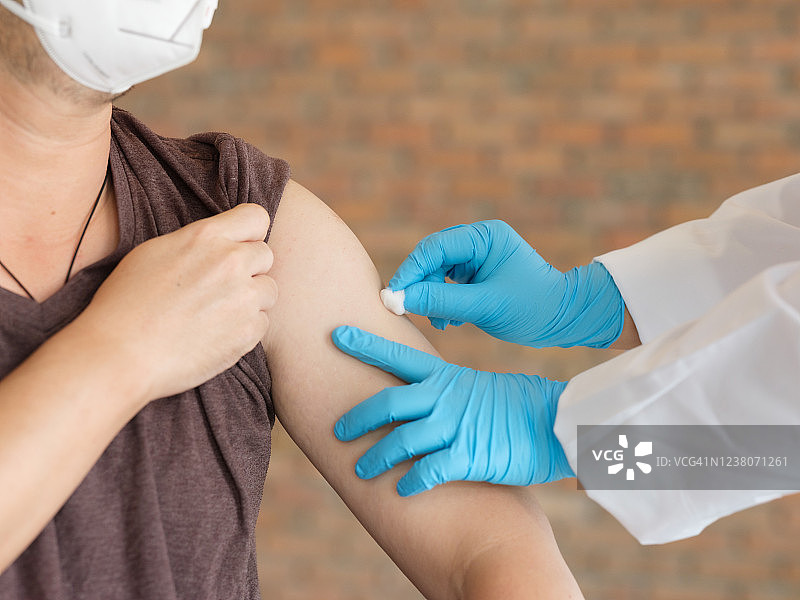 医生在注射前用棉球擦拭男病人的手臂图片素材