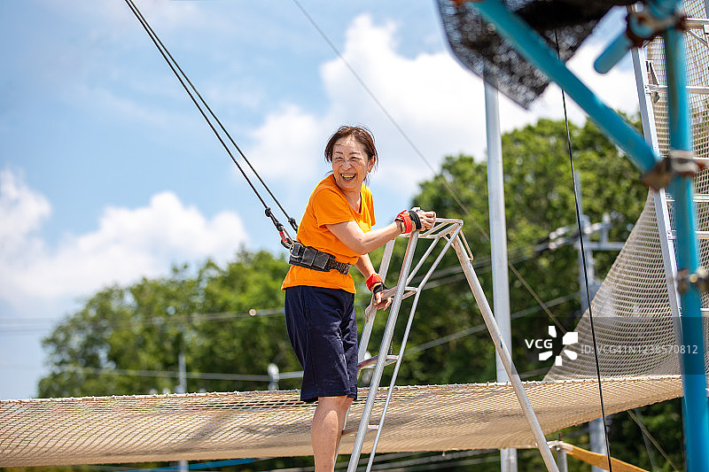 中年妇女在具有挑战性的高空秋千后露出灿烂的笑容图片素材