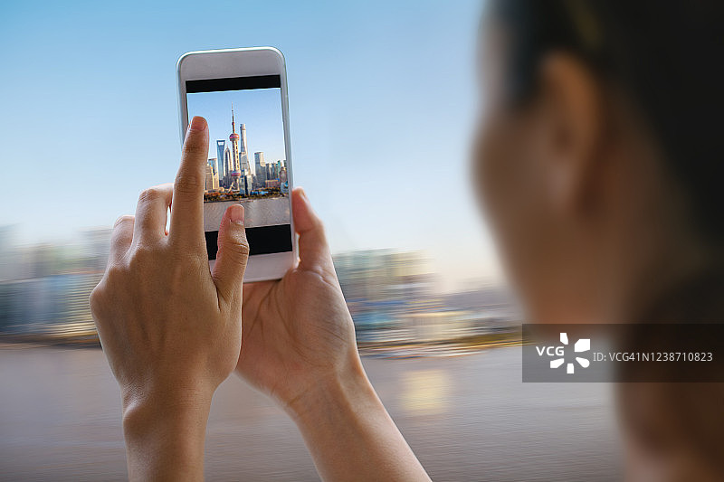 年轻的中国女人用手机拍摄东方明珠塔图片素材