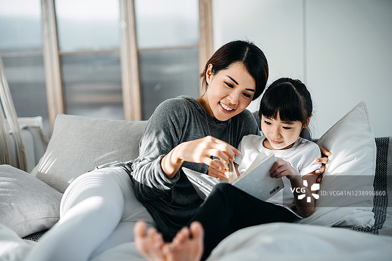 亚洲妈妈在床上给女儿讲故事图片素材