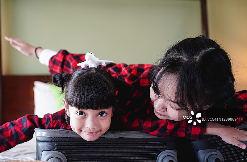 快乐的亚洲母亲和女儿准备旅行，游客摆出飞行姿势，家庭旅行概念图片素材