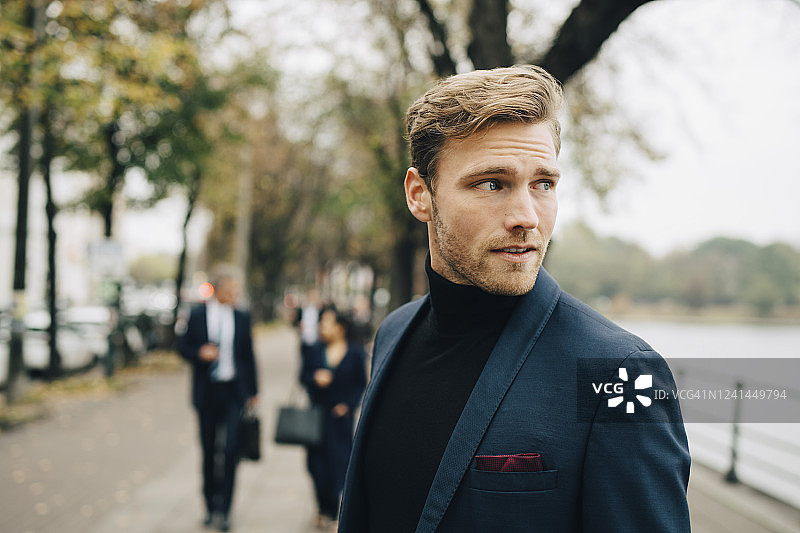 沉思的商务人士站在城市中眺望远方图片素材