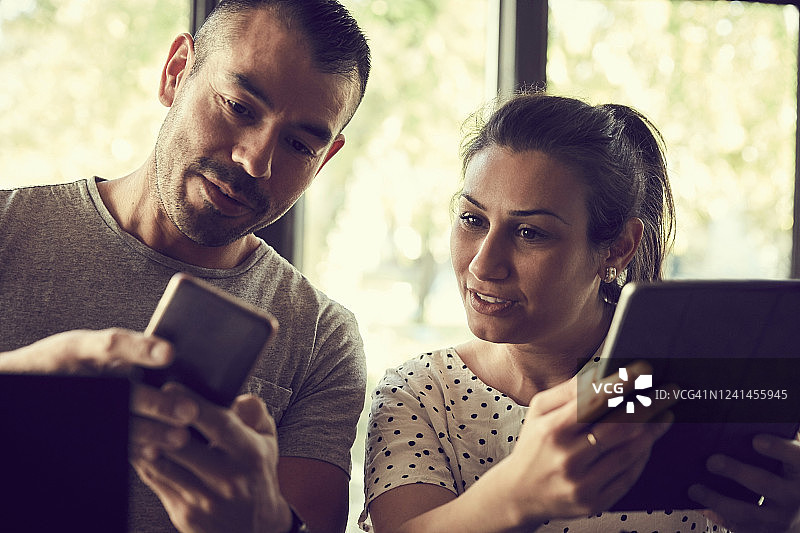 在咖啡馆里，男人向女伴展示手机图片素材