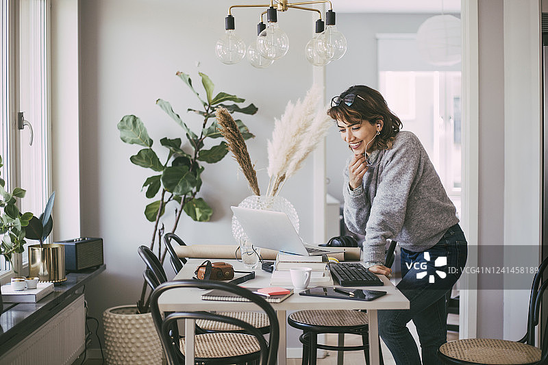 笑容满面的女人在家工作时打电话图片素材