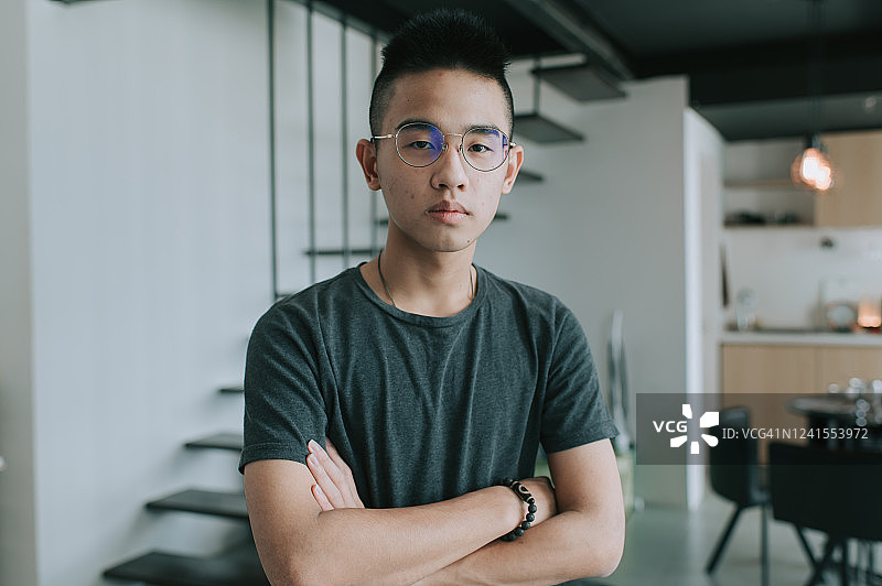 一位表情严肃的亚洲华人少年看着镜头，双手交叉图片素材