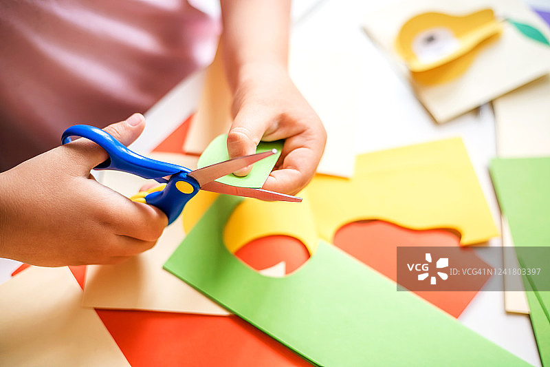 小女孩在桌子上剪彩纸图片素材