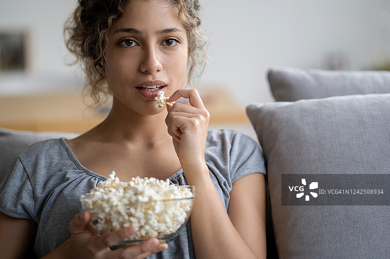隔离期间吃爆米花看电视的女人图片素材