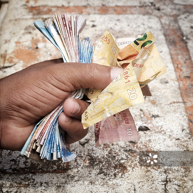 手握巴西货币，象征着非正规经济图片素材