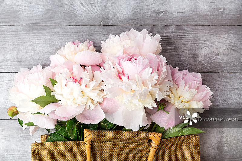 灰色背景上带粉色牡丹花的草编包图片素材
