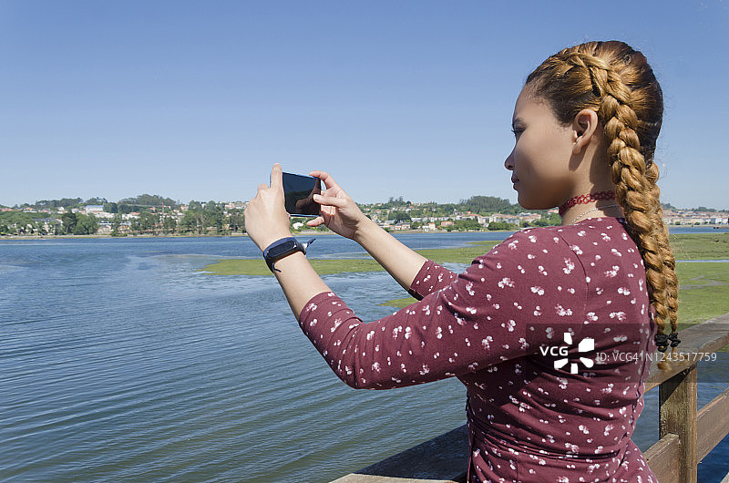 年轻女子拍摄美丽的夏日风景照片图片素材