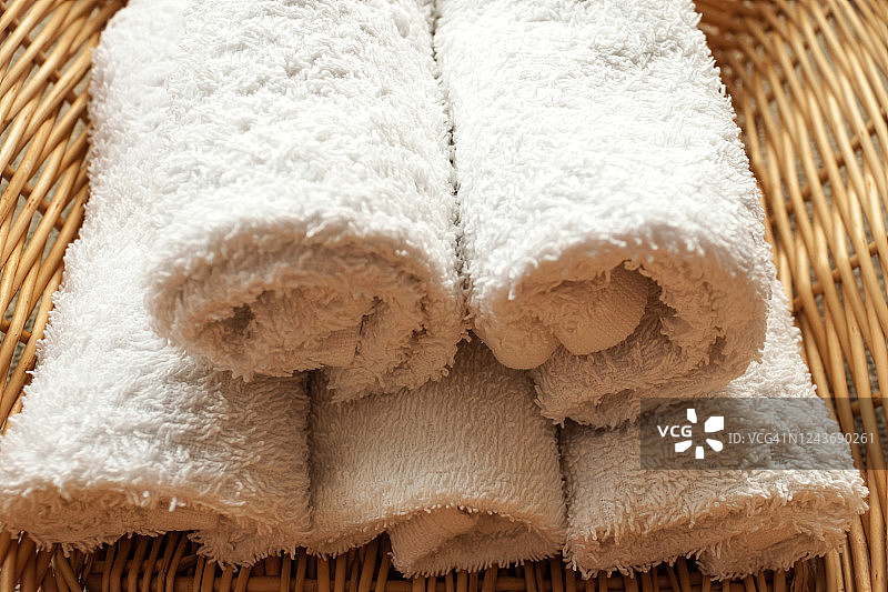 柳条筐背景上的白色干净卷曲毛巾堆叠特写图片素材