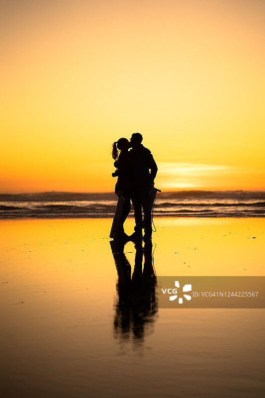 情侣在日出时分的海滩上亲吻图片素材