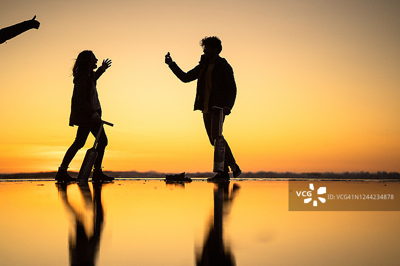 朋友们在日出时分于海滩上寻找蛤蜊图片素材