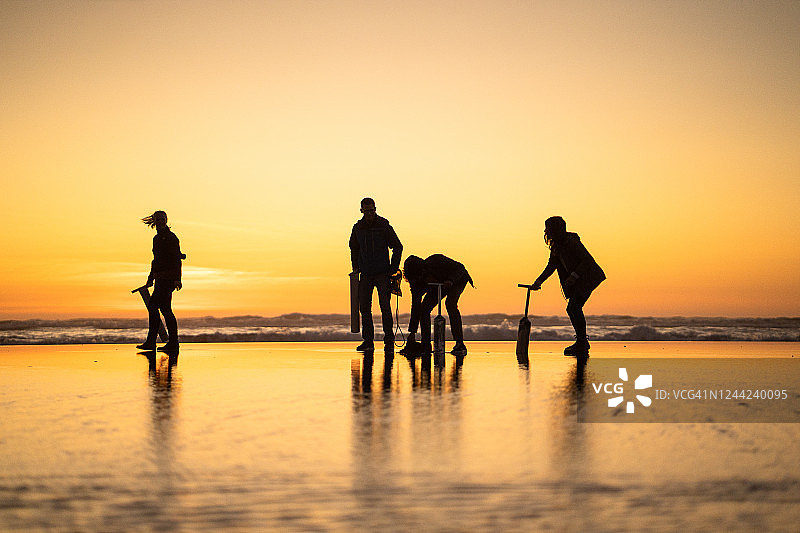 朋友们在日出时分于海滩上寻找蛤蜊图片素材