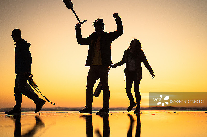 朋友们在日出时分于海滩上寻找蛤蜊图片素材