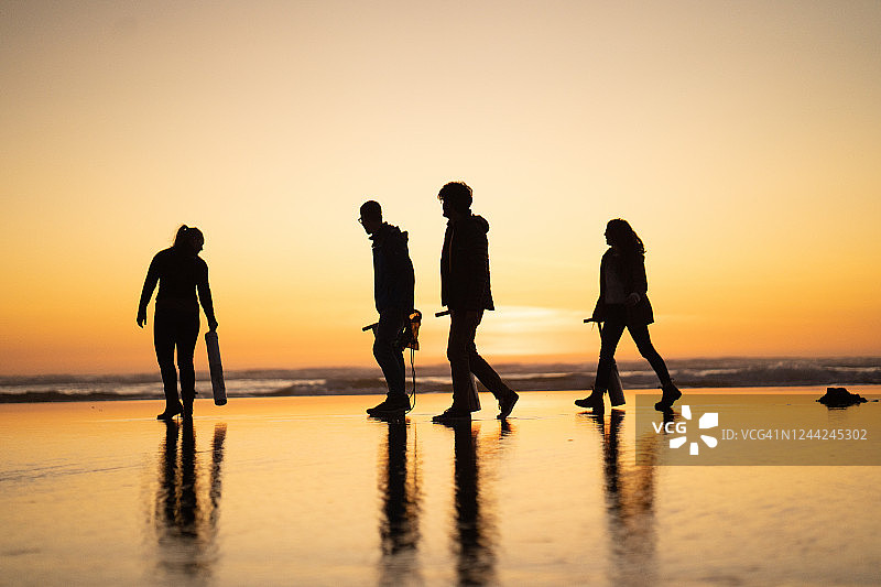 朋友们在日出时分于海滩上寻找蛤蜊图片素材