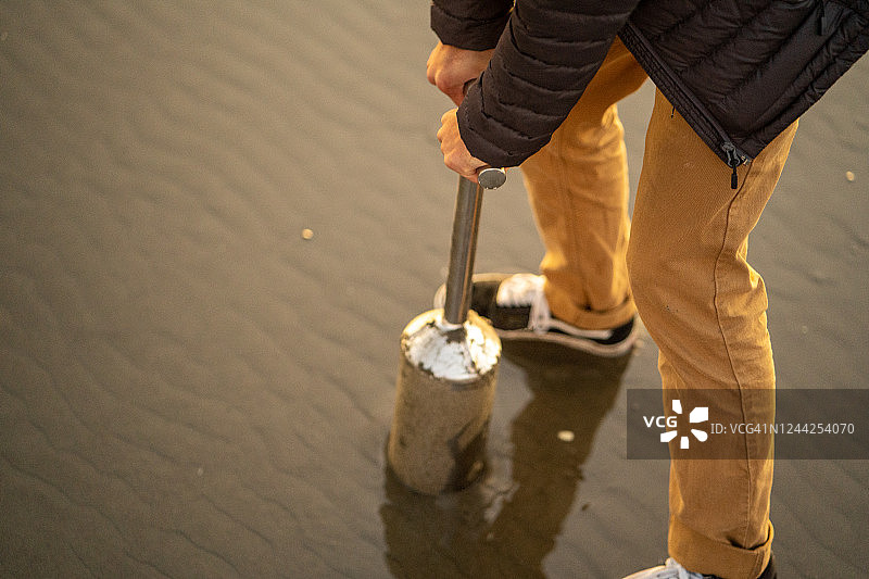 年轻男人在海滩上挖蛤蜊图片素材