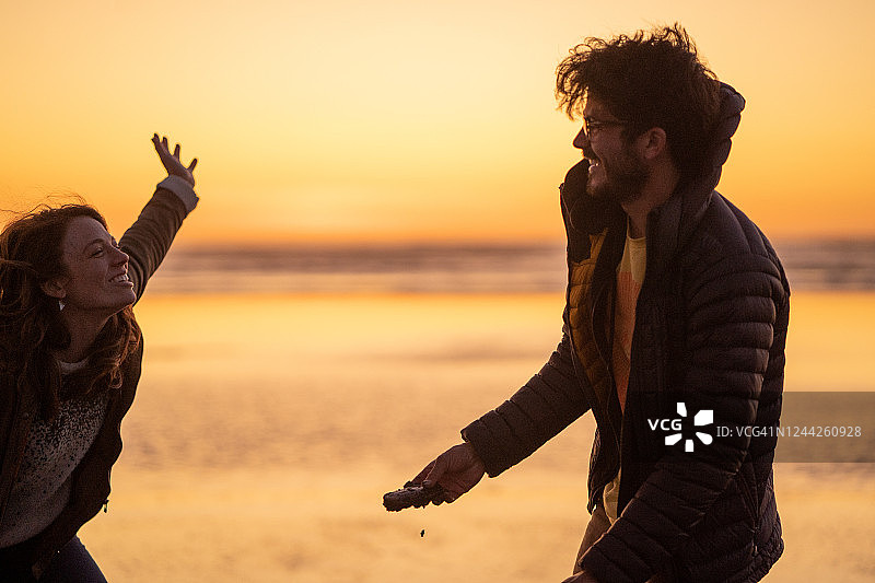 朋友们在日出时分的沙滩上聊天欢笑图片素材