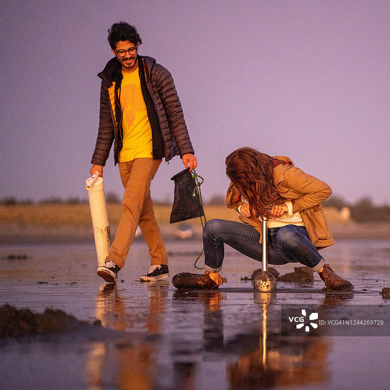 朋友们在日出时分于海滩上寻找蛤蜊图片素材