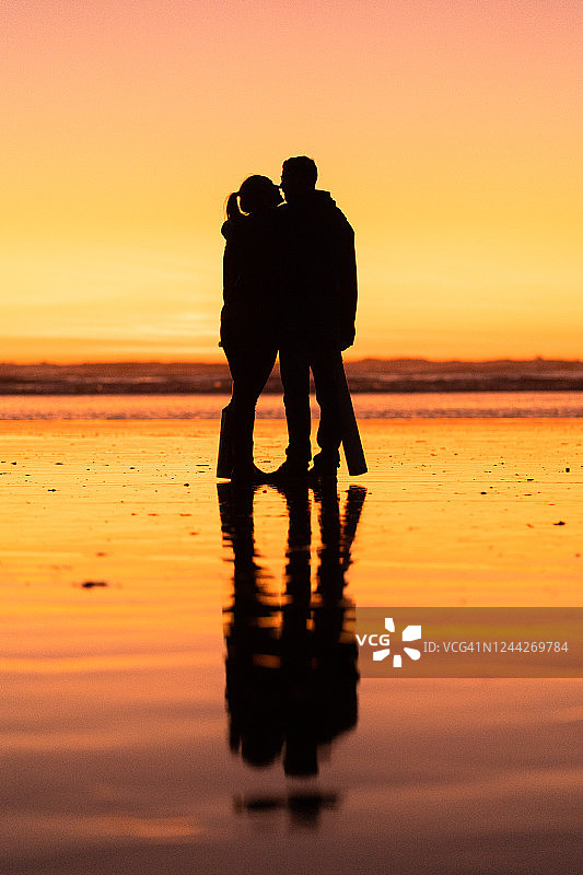 日出时分情侣在海滩上亲吻图片素材