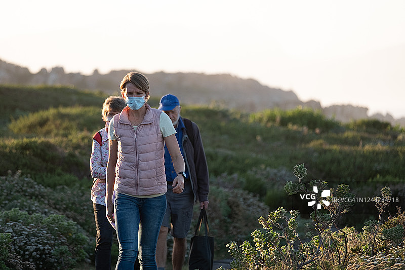 女人和年迈的父母沿着海边小路散步图片素材