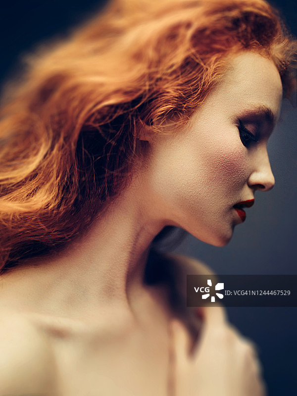 向下看的沉思的年轻红发女子图片素材