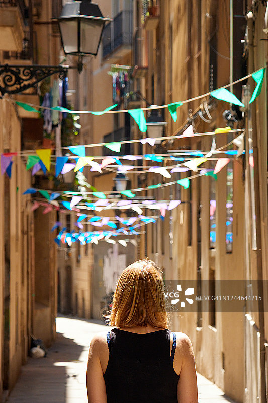 巴塞罗那哥特区街道上，上方悬挂着彩旗的女人图片素材