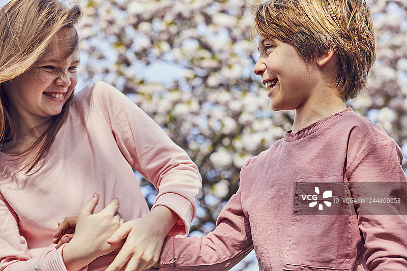 在户外互相逗弄的微笑的深色头发男孩和女孩图片素材