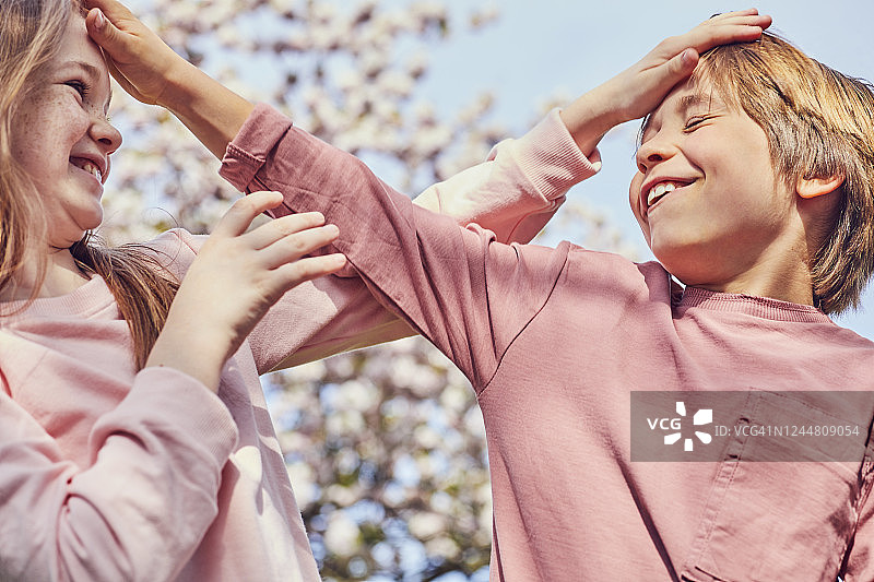 在户外互相逗弄的微笑的深色头发男孩和女孩图片素材