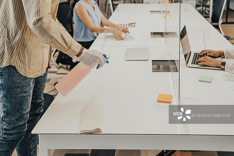 疫情期间在办公室用消毒剂擦拭显示器的男人图片素材